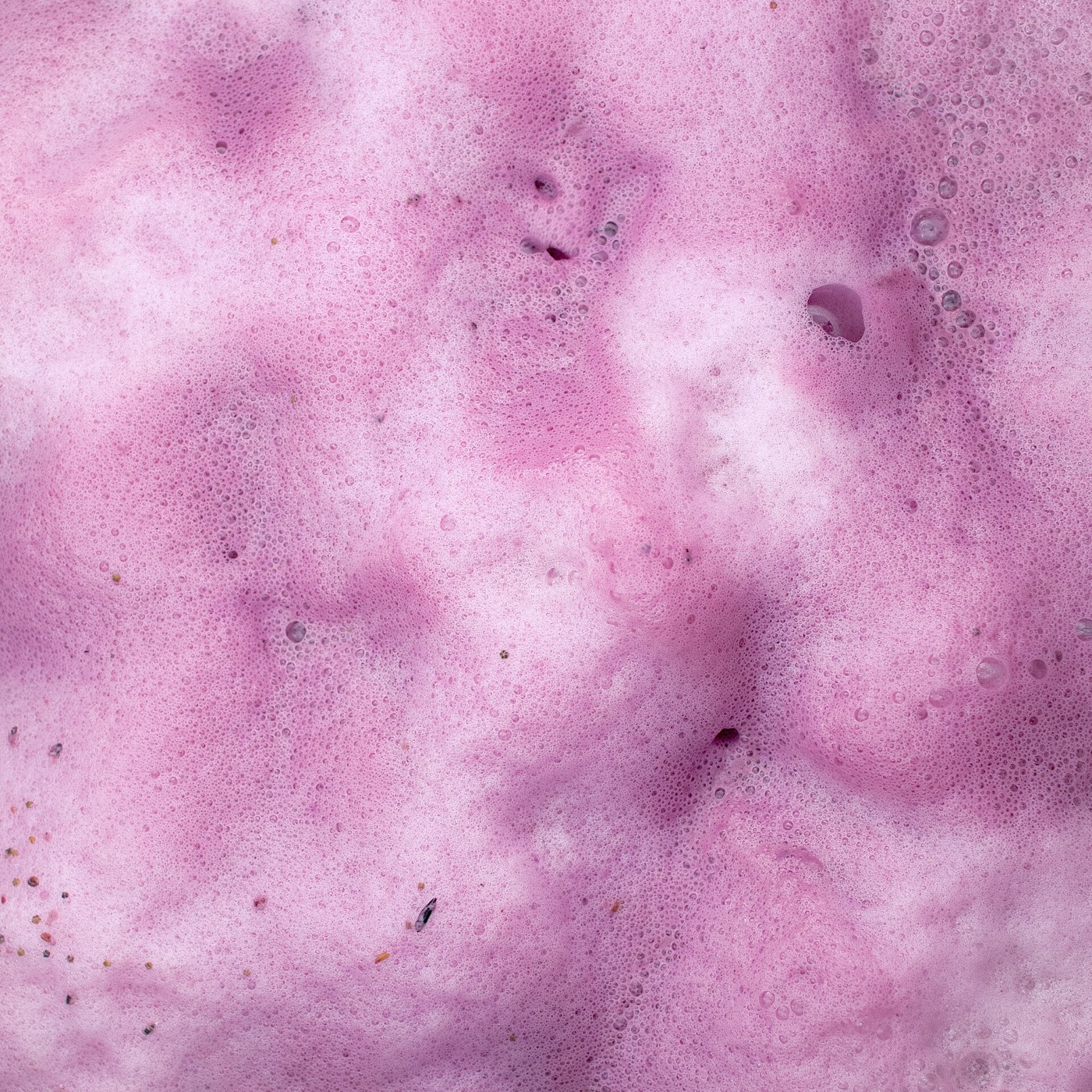 Pale pink rosé juice actively fermenting in a winery vessel.